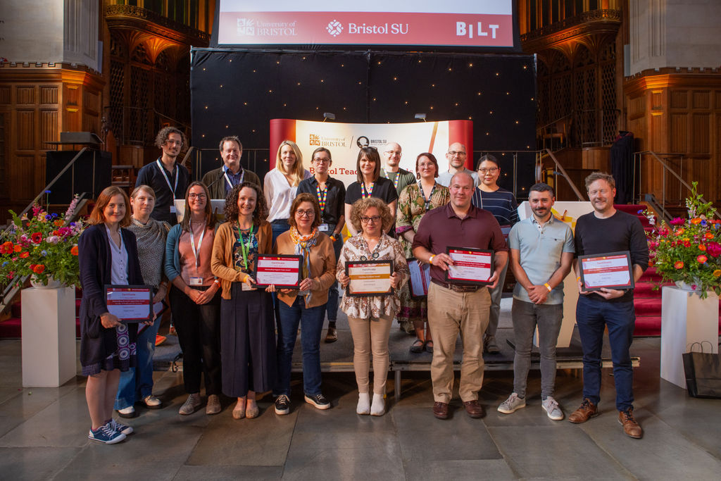 The winners of the Bristol Teaching Awards 2024 standing with their certificates in the Great Hall of the University of Bristol's Wills Memorial Building.